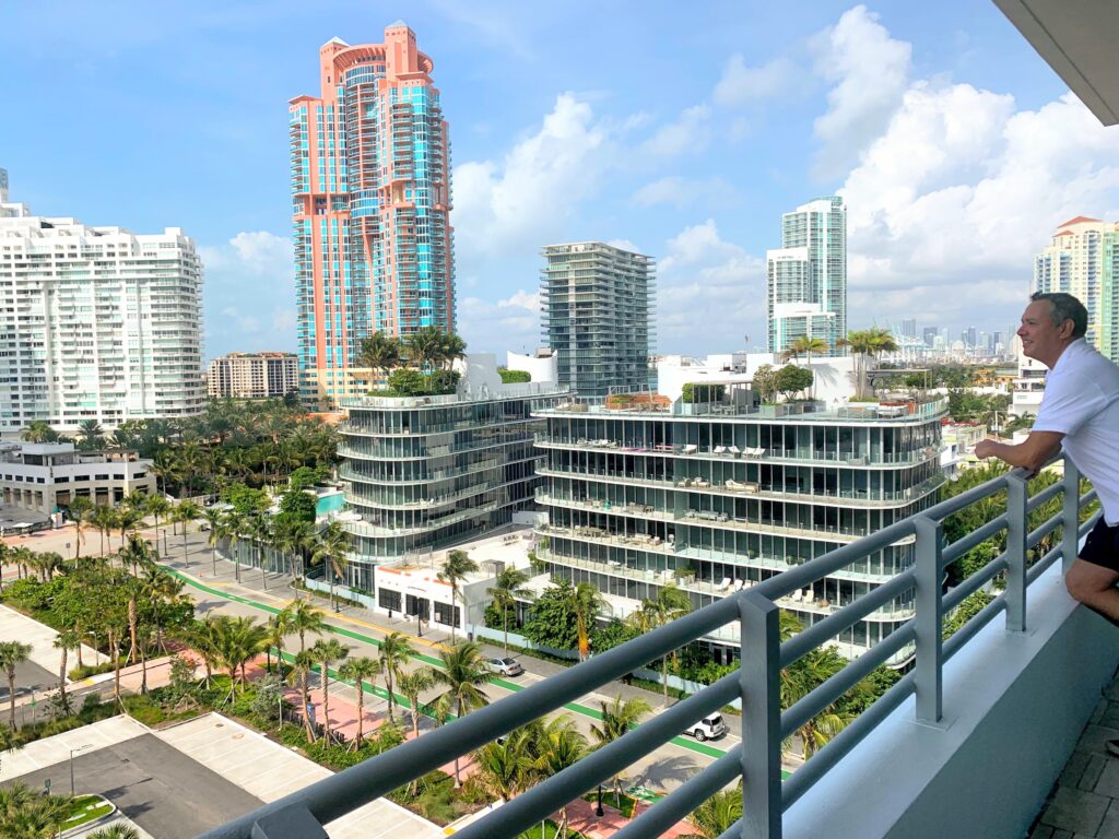 Vista panorámica de South Beach desde un hotel frente al mar, con arena blanca, palmeras y el océano turquesa.